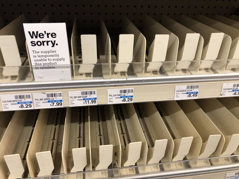 A sign stands in front of the empty shelves for children’s Tylenol reading, “sorry the supplier is temporarily unable to supply this product.”