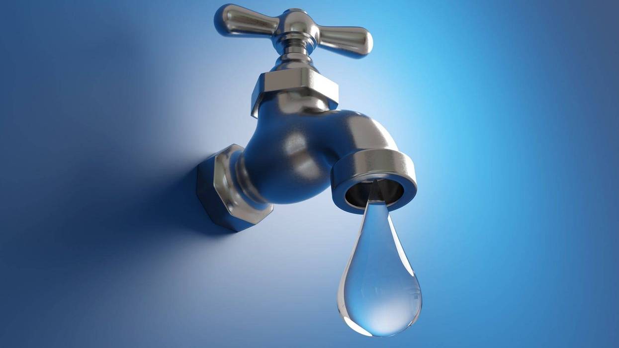 A silver water faucet dripping a large water droplet on blue background
