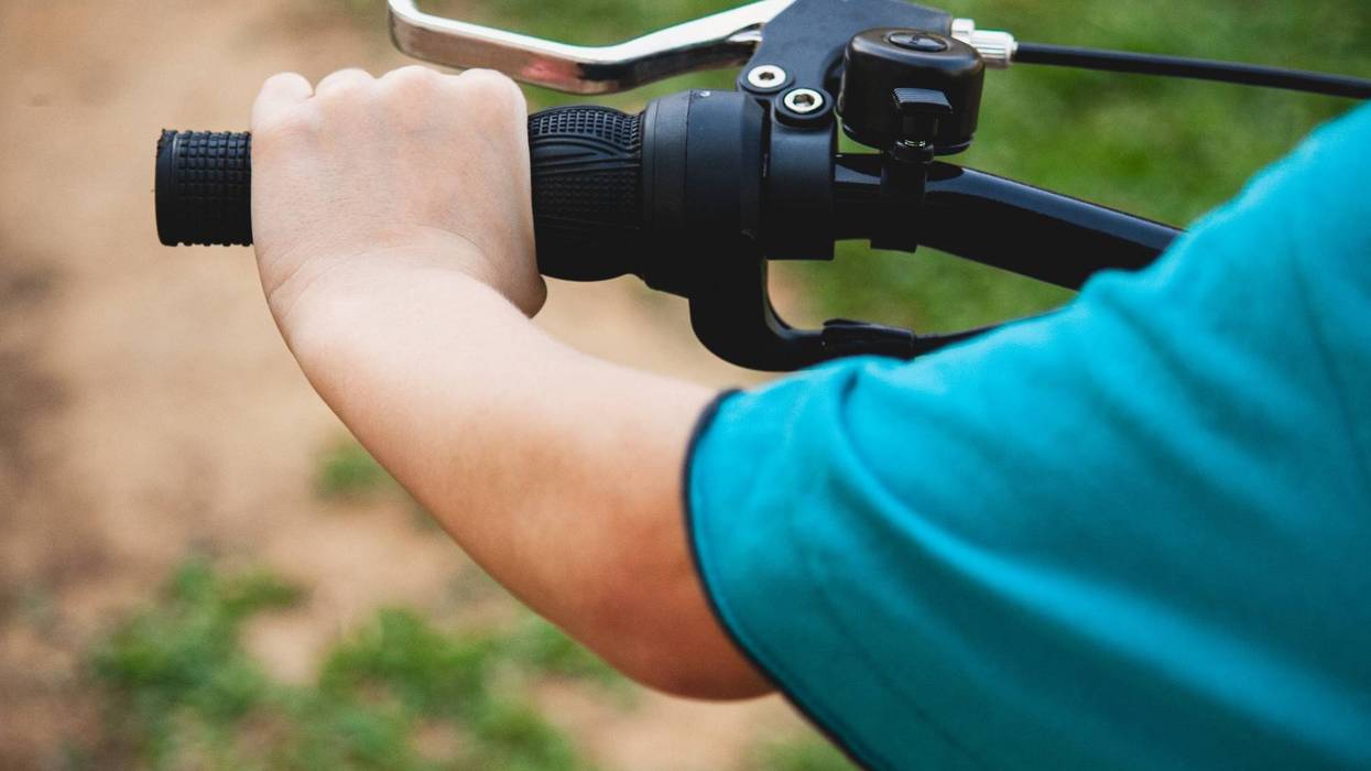 A small child grabbing onto a bike handle