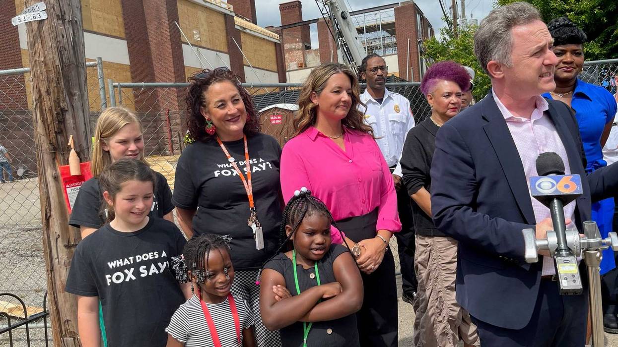 A small group of kids and adults in front of a contruction site