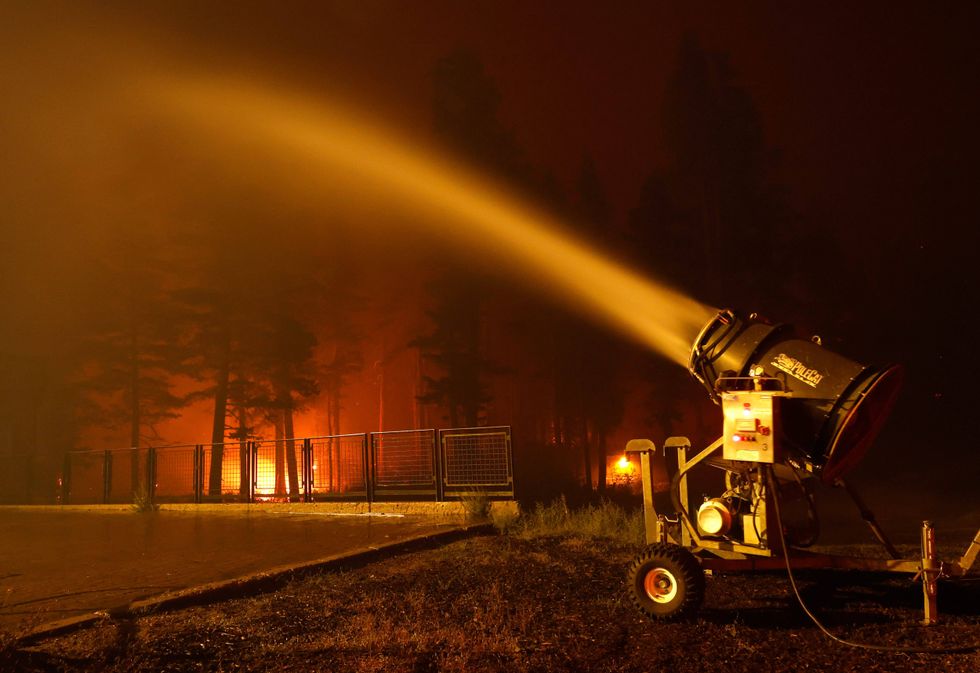A snow machine blows water on a structure at Sierra-at Tahoe ski resort as the Caldor Fire moves through the area on August 30, 2021 in Twin Bridges, California.