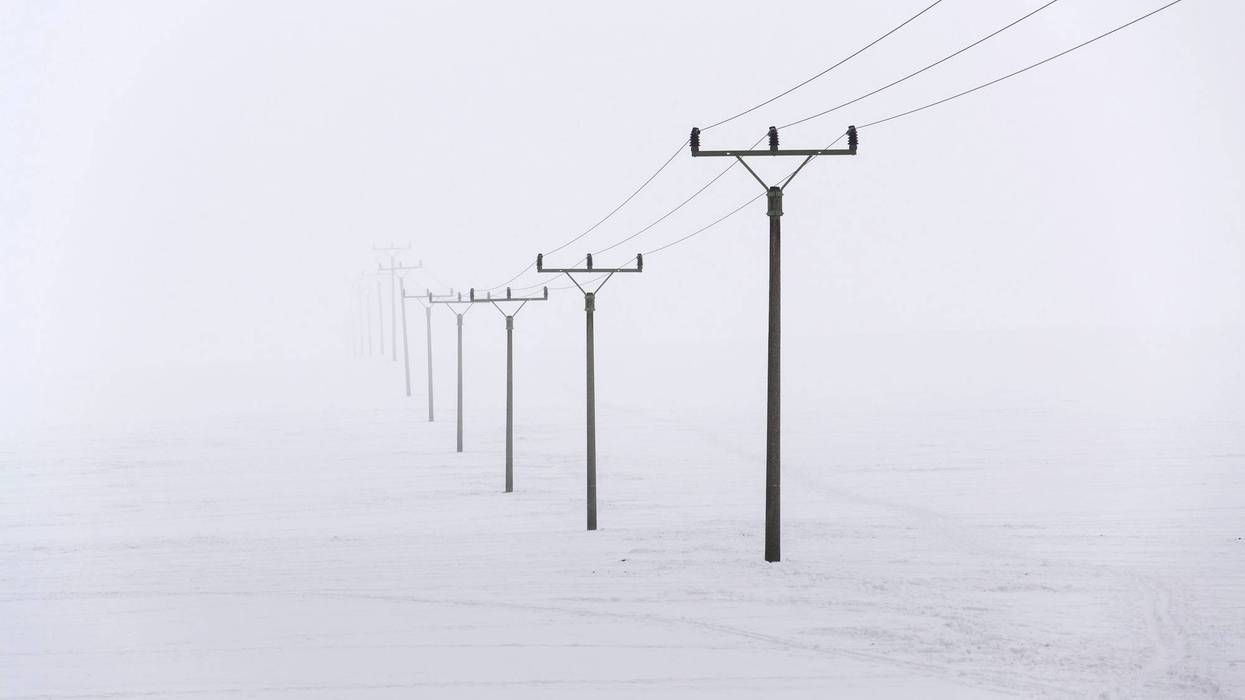 A snowy field with power lines stretching off to the distance