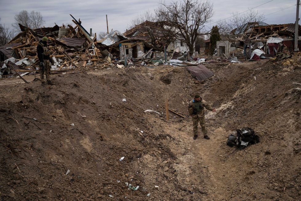 A soldier stands inside a crater made by a bomb near Brovary, on the outskirts of Kyiv, Ukraine, Monday, March 28, 2022