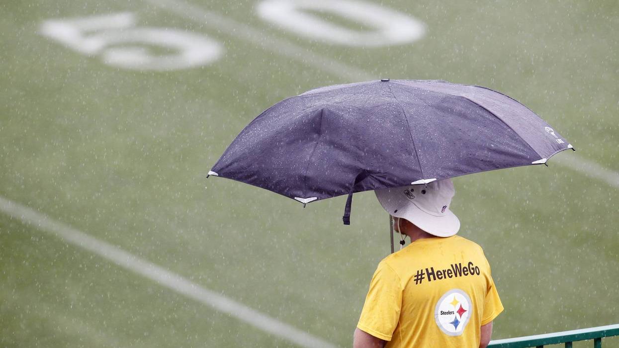 A staff member looks over the fields as rain delays the start of Pittsburgh Steelers training camp