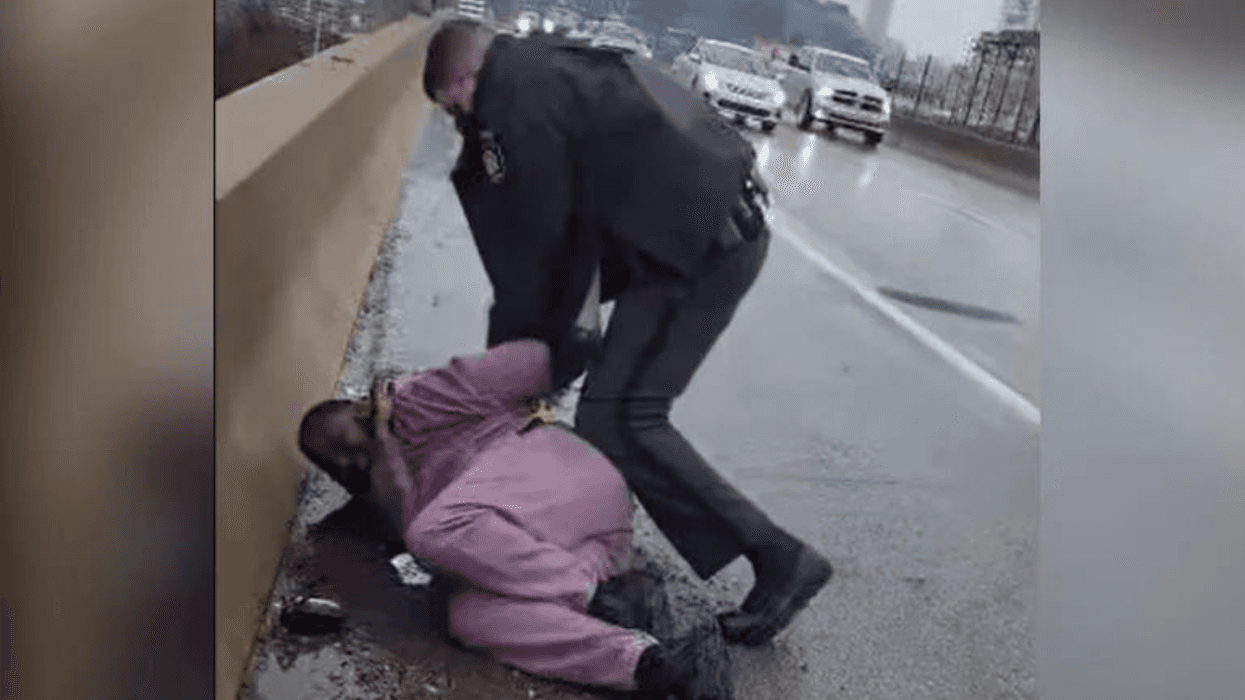 A state trooper arrests a man curled up on the shoulder of the Vine Street Expressway.