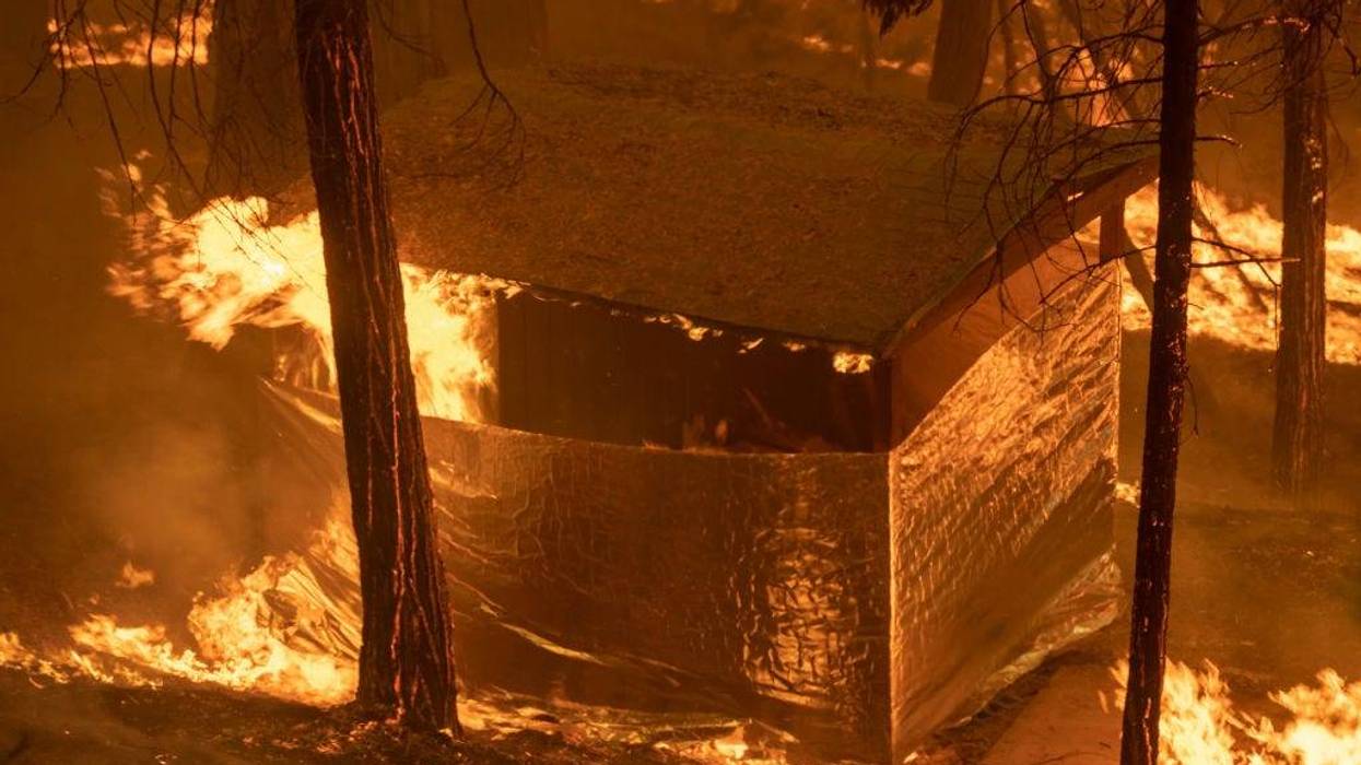 A structure that firefighters had covered with structure wrap in hopes that it might survive catches fire in Slick Rock Canyon as the French Fire continues to spread.