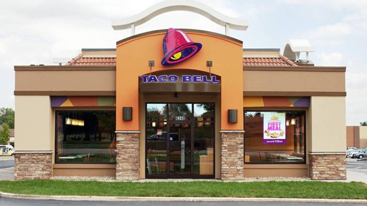 A Taco Bell restaurant with an orange facade, large pink bell logo, and stone accents.