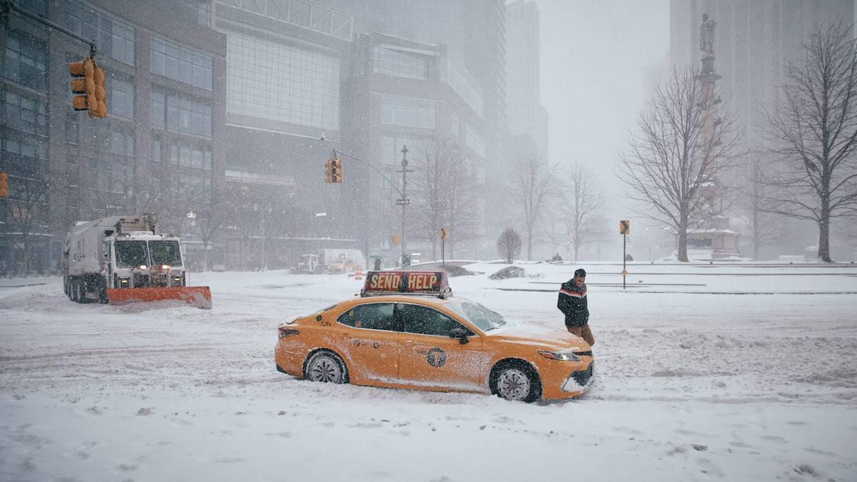 A taxi driver gets out of his car after it becomes stuck in the snow at Columbus Circle on Jan. 25, 2026