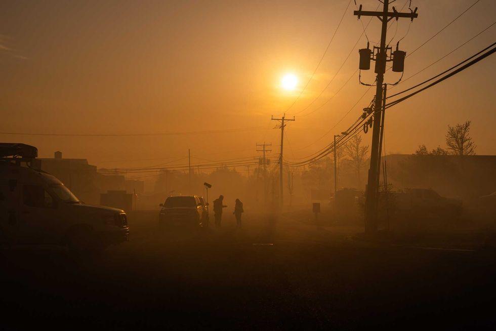 A television crew is shrouded in the smoke from a wildfire on April 24, 2025, in Forked River, New Jersey