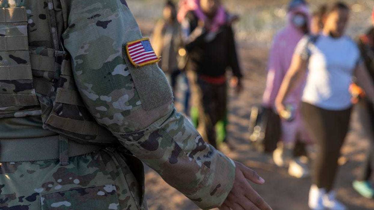 A Texas National Guard soldier observes as thousands of immigrants walk towards a U.S. Border Patrol transit center on December 19, 2023 in Eagle Pass, Texas.