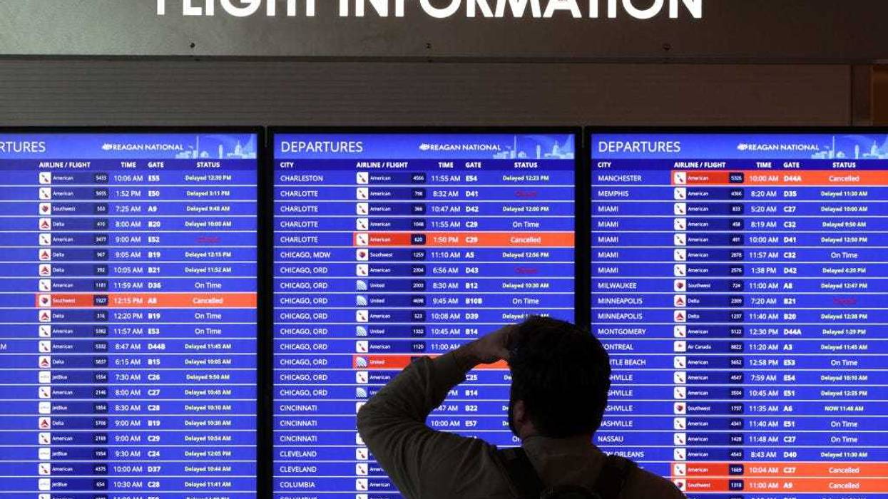 A traveler looks at a flight information board at Ronald Reagan Washington National Airport on January 11, 2023 in Arlington, Virginia. The FAA said it is gradually resuming flights around the country after an outage to the Notice to Air Mission System, a computer system that helps guide air traffic. (Photo by Alex Wong/Getty Images)