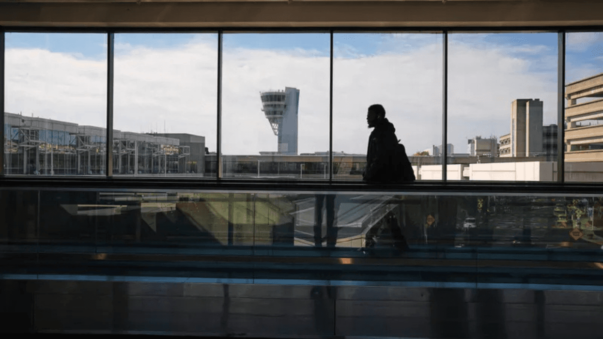 A traveler moves in view of a control tower at Philadelphia International Airport on Nov. 5, 2025.