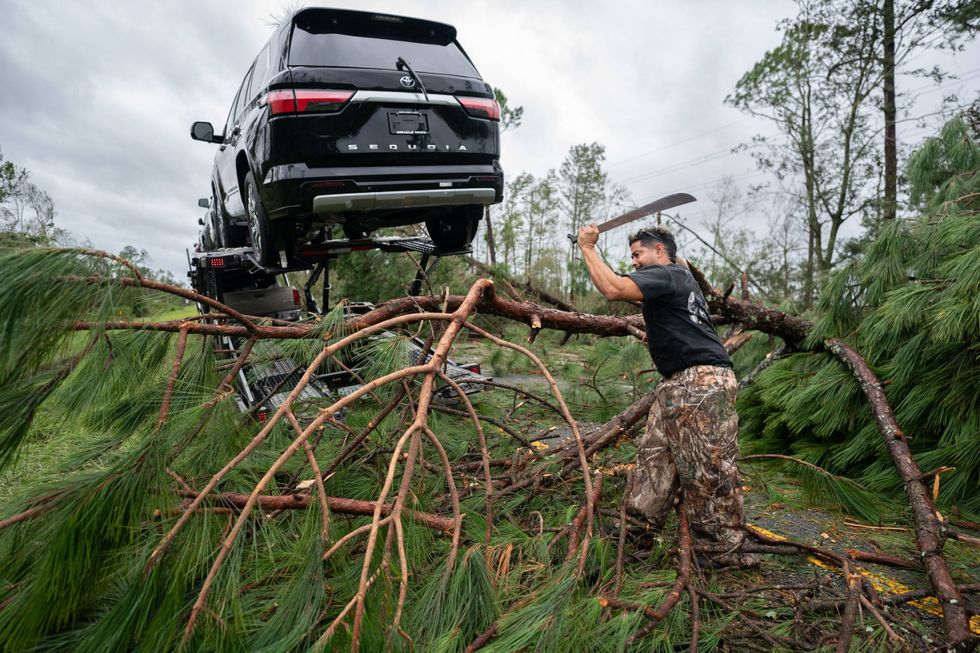 A truck driver uses a machete to clear I-10 of fallen trees and branches after Hurricane Idalia crossed the state on August 30, 2023 near Madison, Florida.