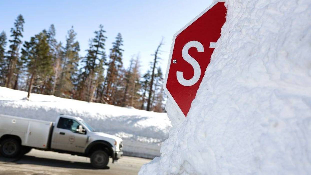 A truck passes by a stop sign that is buried in snow on March 03, 2023 in Twin Bridges, California.