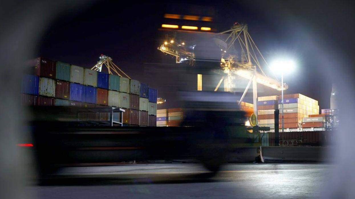 A truck passes shipping containers at the Port of Los Angeles during nighttime operations on October 25, 2021, in San Pedro, California.