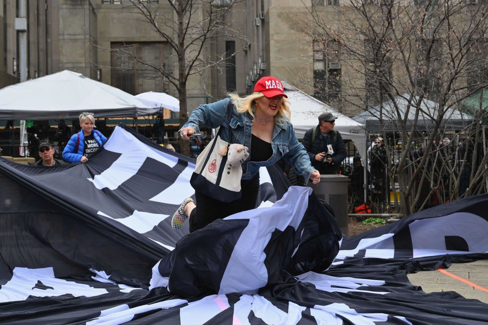 A Trump supporter rushes an anti-Trump banner outside Manhattan Criminal Court on April 4, 2023
