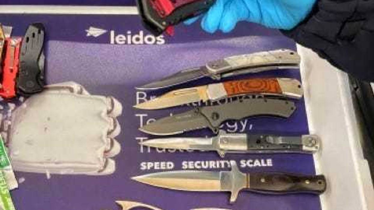 A TSA officer picks up a knife, one of many weapons that were detected in a traveler’s carry-on bag at DCA on May 4.