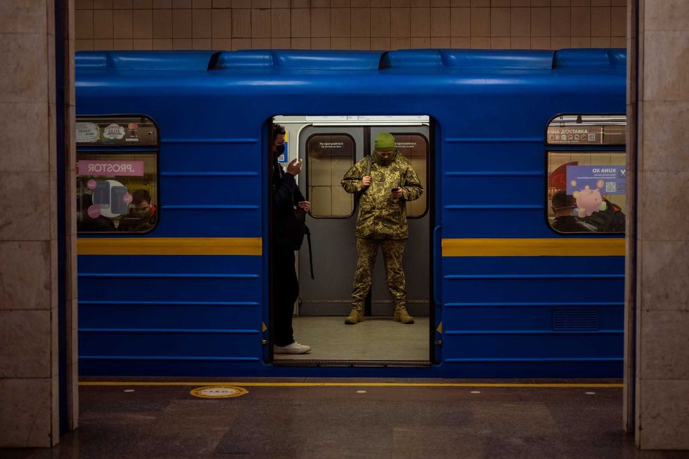 A Ukrainian army officer looks at his phone in a local train in Kyiv, Ukraine, Wednesday, Feb. 23, 2022