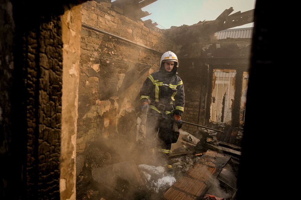 A Ukrainian firefighter stands in the ruins of a house destroyed by bombing in Kyiv, Ukraine, Wednesday, March 23, 2022
