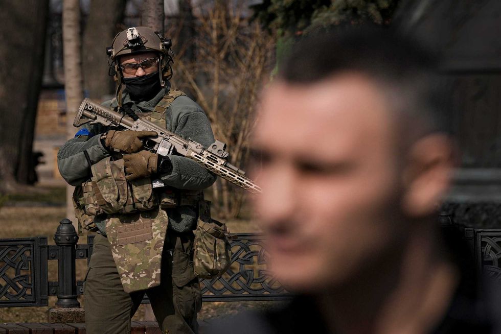A Ukrainian serviceman guards the area as Kyiv Mayor Vitali Klitschko, foreground, speaks during a press conference in Kyiv, Ukraine,Wednesday, March 23, 2022