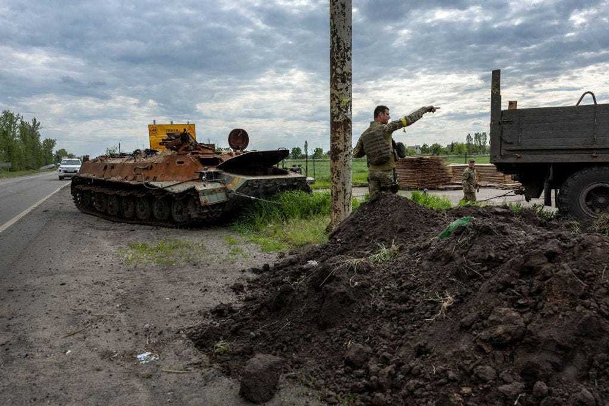 A Ukrainian soldier directs a driver towing a burnt Russian armored personnel carrier on May 25, 2022 in Kharkiv, Ukraine. Although Russian shelling has largely ceased in the city, the attacks destroyed many houses and large apartment buildings, especially in the northern part of the city, leaving thousands of residents without utilities or homeless. (Photo by John Moore/Getty Images)