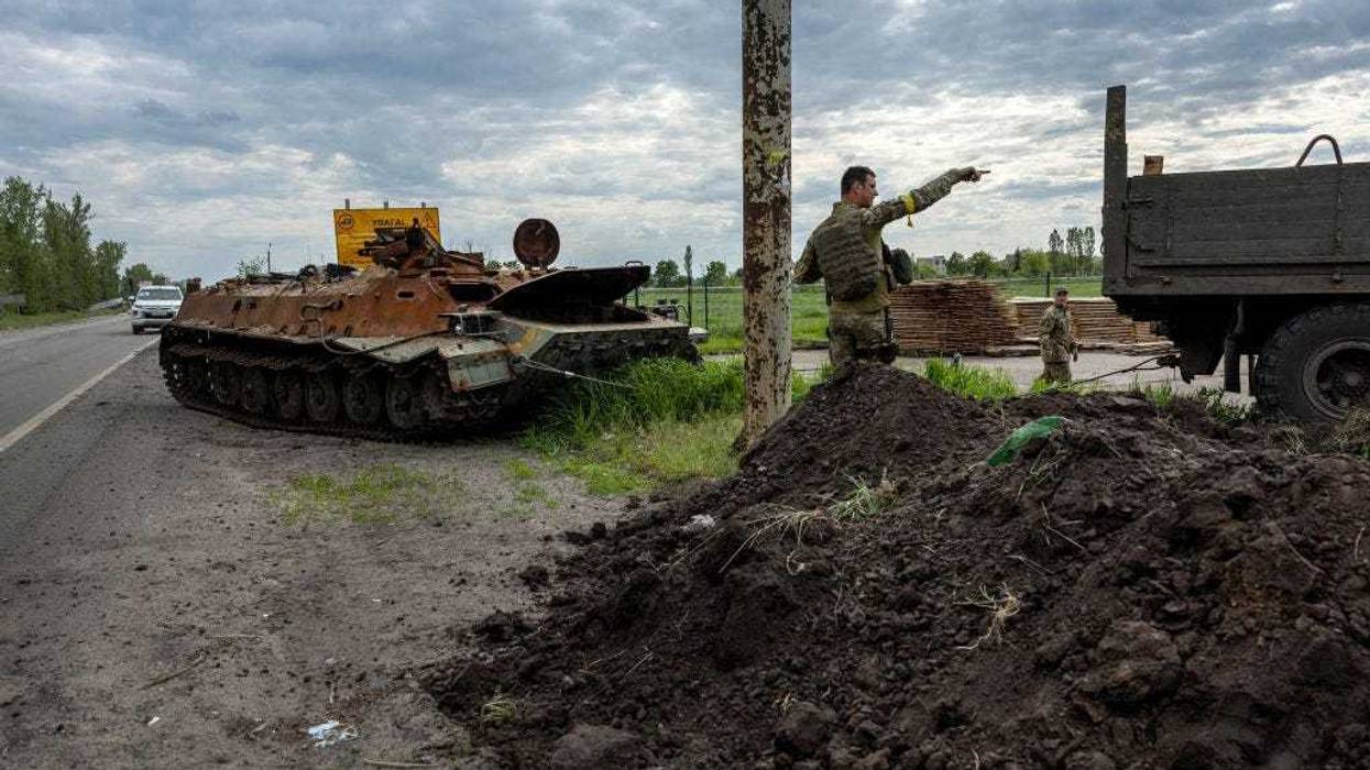 A Ukrainian soldier directs a driver towing a burnt Russian armored personnel carrier on May 25, 2022 in Kharkiv, Ukraine. Although Russian shelling has largely ceased in the city, the attacks destroyed many houses and large apartment buildings, especially in the northern part of the city, leaving thousands of residents without utilities or homeless. (Photo by John Moore/Getty Images)