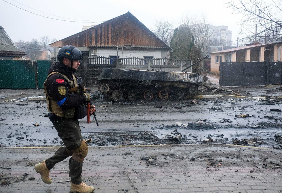 A Ukrainian soldier inspects the wreckage of a destroyed Russian armored column on a road in Bucha, a suburb just north of the Capital, Kyiv, on April 3, 2022