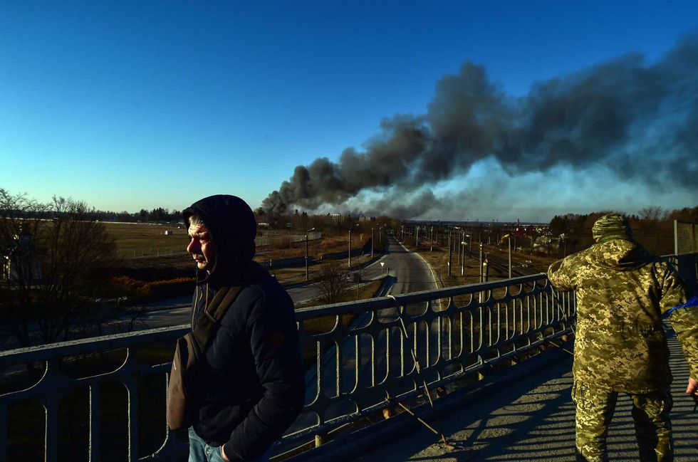 A Ukrainian soldier watches as smoke raises after an explosion near the airport, in Lviv, western Ukraine, Friday, March 18, 2022