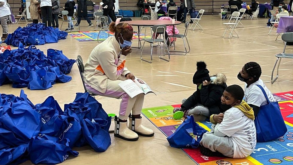 A volunteer reads a book to some kids who just got a COVID-19 vaccination.