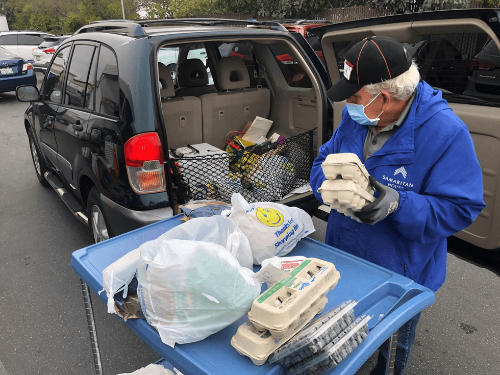 A volunteer working at The Samaritan House in San Mateo loads food into a vehicle.