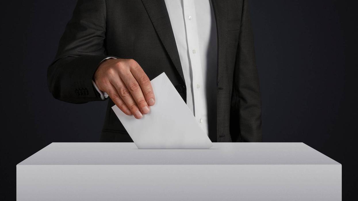 A voter dropping a ballot in a ballot box.