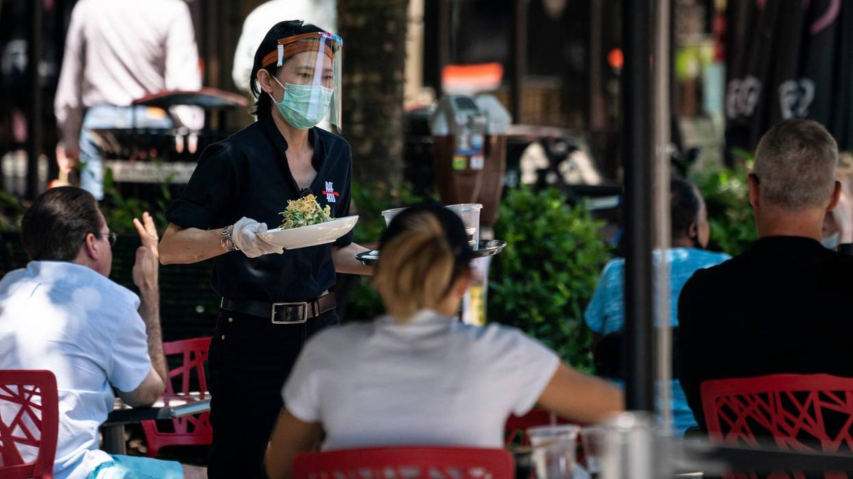 A waiter at Raku, an Asian restaurant in Bethesda, wears a protective face mask as serve customers outdoors amid the coronavirus pandemic on June 12, 2020 in Bethesda, Maryland.