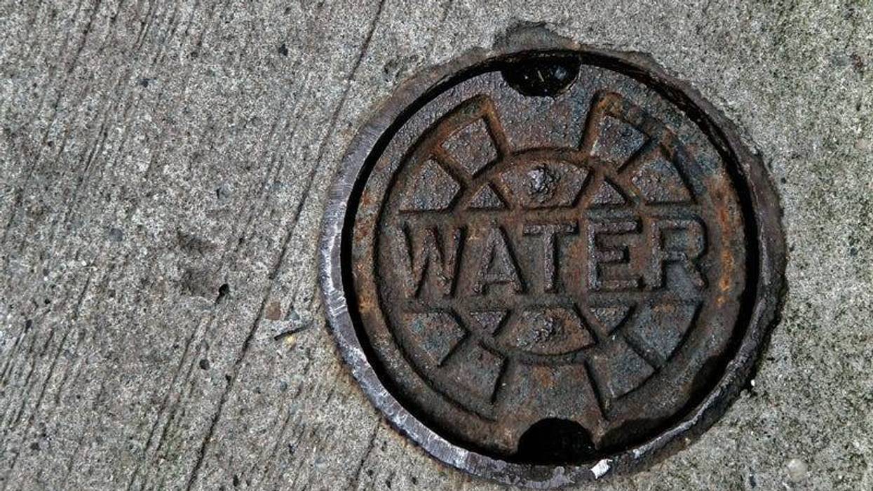 A water main manhole cover on pavement.