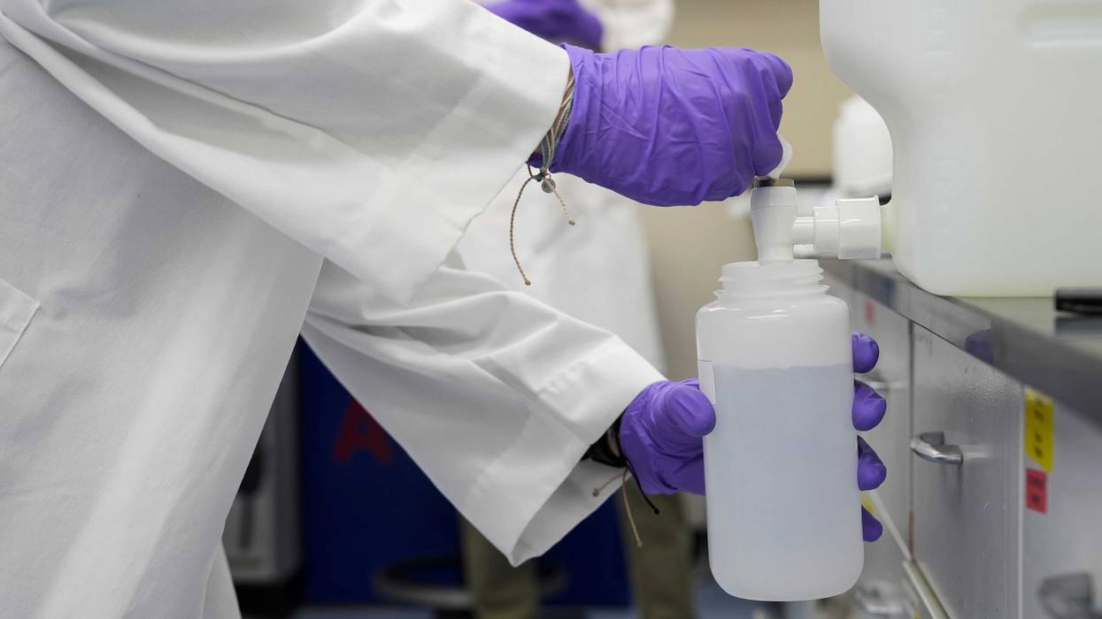 A water sample with forever chemicals, known as PFAS, into a container for research at a U.S. Environmental Protection Agency lab.