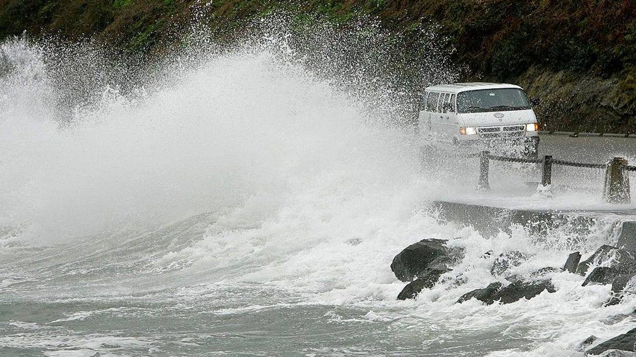 A wave crashes against rocks and a van driving by near the Golden Gate Bridge December 28, 2005 in San Francisco.
