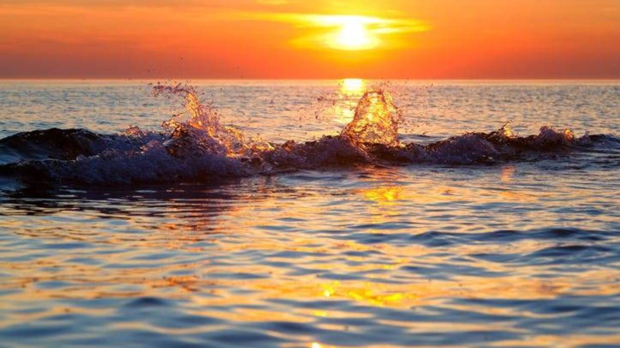 A wave splashes at sunset on Lake Michigan in Ludington State Park.