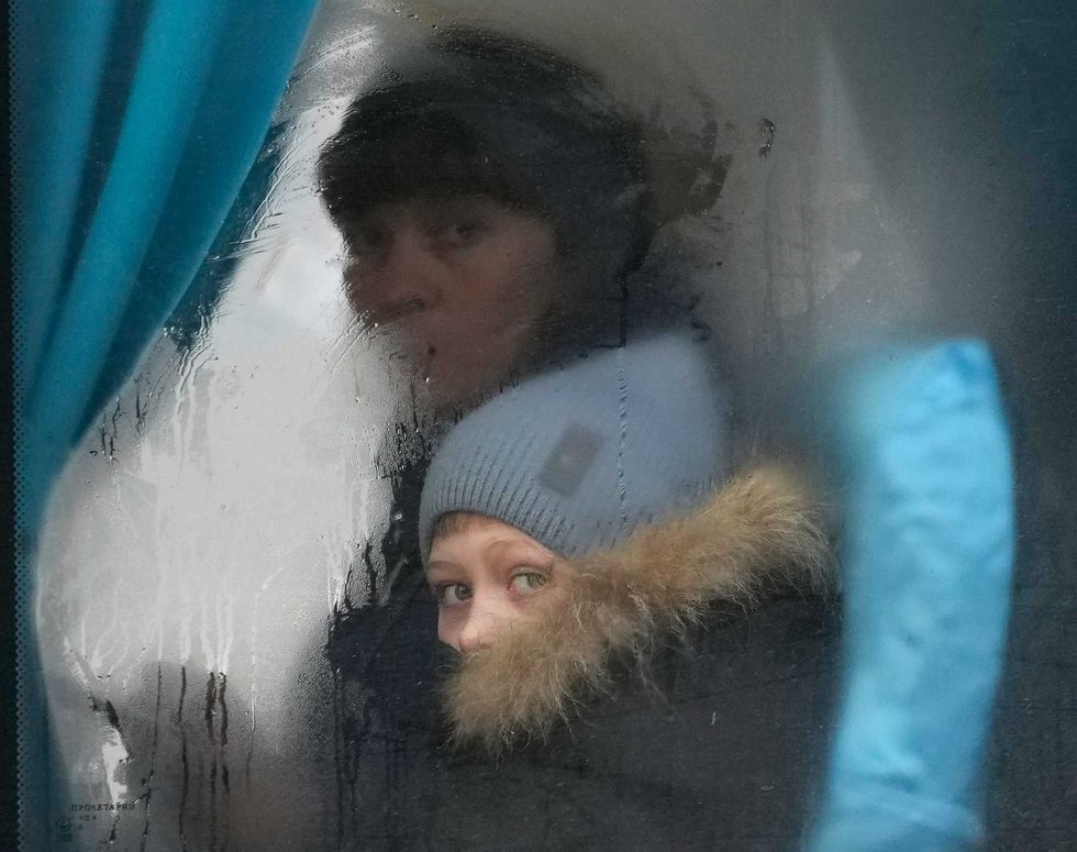 A woman and child peer out of the window of a bus as they leave Sievierodonetsk, the Luhansk region, in eastern Ukraine, Thursday, Feb. 24, 2022