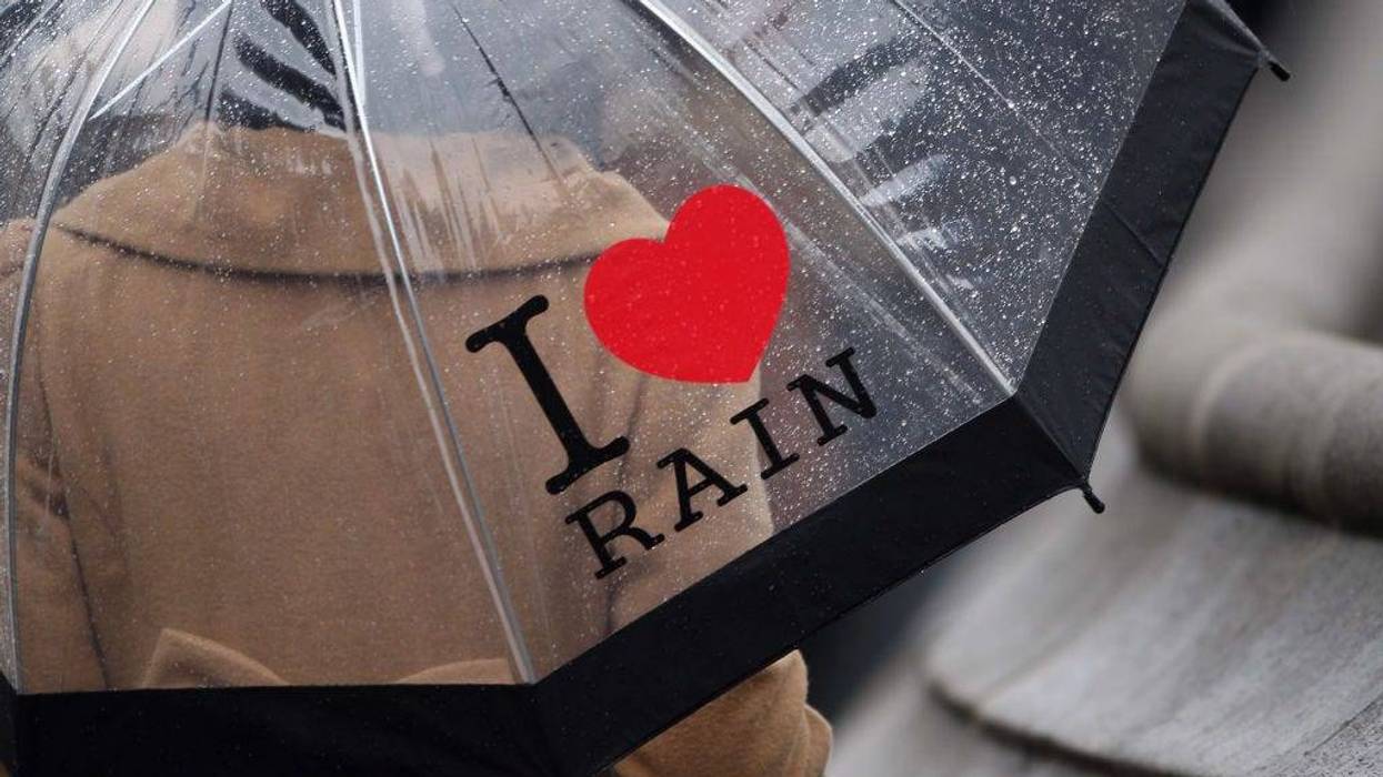 A woman carrying an umbrella that reads I love rain, walks across Parliament Square on November 8, 2010 in London, England.