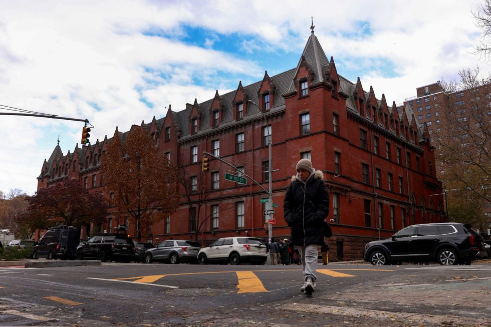 A woman crosses Amsterdam Avenue outside the HI New York City hostel, Thursday, Dec. 5, 2024, in New York, where police say the suspect in the killing of UnitedHealthcare CEO Brian Thompson may have stayed