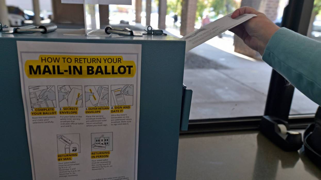 A woman drops her mail-in ballot into the drop box at the Luzerne County Board of Elections on Oct. 22, 2020.