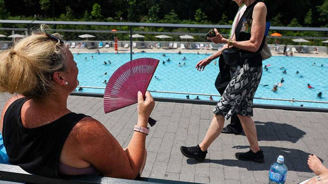 A woman fans herself by the newly opened Gottesman Pool at the Davis Center in Harlem Meer on a day that saw temperatures reach into the mid-90's with a heat index over 100 degrees July 17, 2025 in NYC.