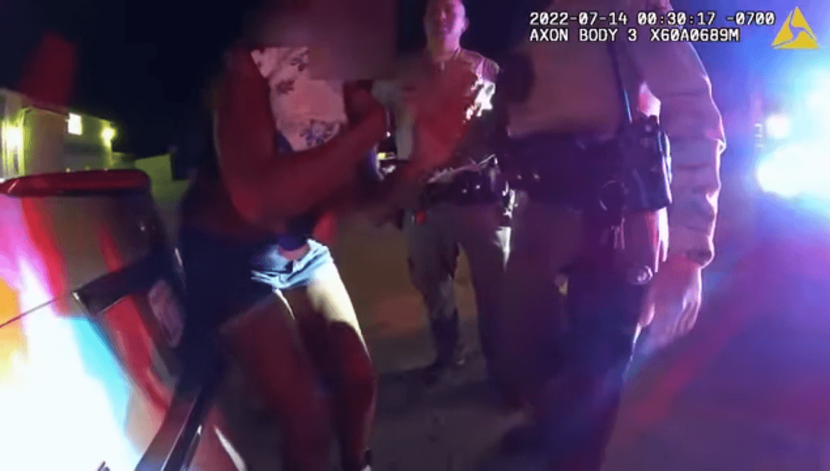 a woman holding a baby surrounded by sheriff's deputies