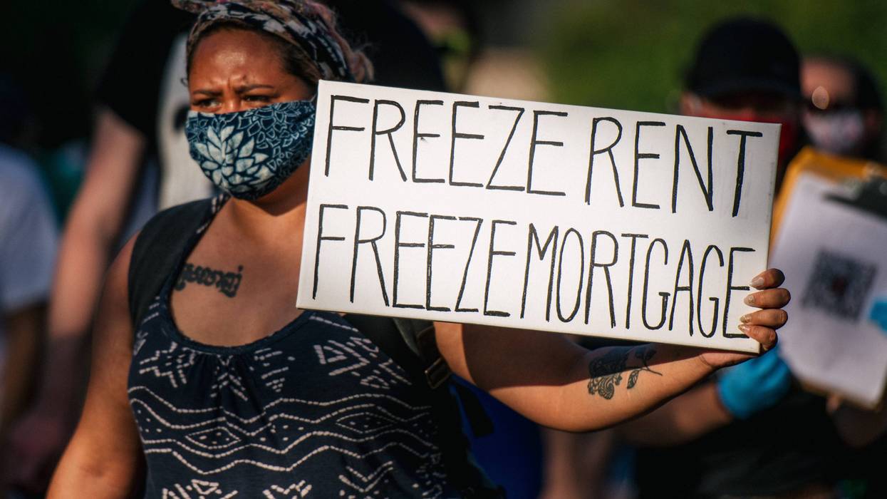 A woman holds a sign up as demonstrators march in the street during the Cancel Rent and Mortgages rally on June 30, 2020 in Minneapolis, Minnesota.