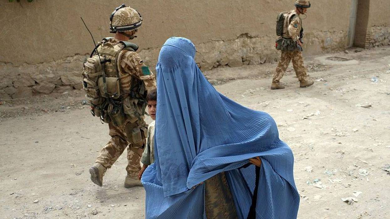 A woman in a burqa and a child walk past two British paratroopers from 3rd Battalion The Parachute Regiment on patrol on June 21, 2008 in Kandahar, Afghanistan