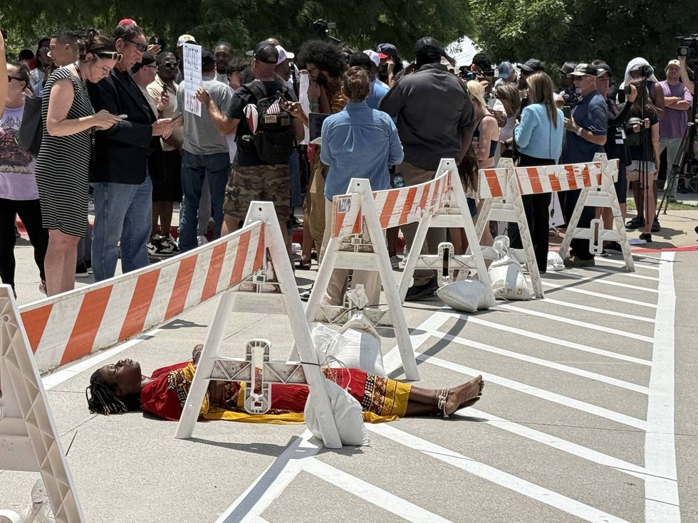 A woman in the ground in the heat as people wait to hear the verdict in the Karmelo Anthony trial held in McKinney at the Collin County courthouse.
