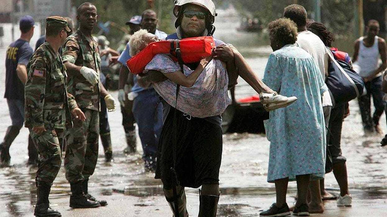 A woman is carried out of flood waters after being trapped in her home in Orleans parish during the aftermath of Hurricane Katrina August 30, 2005 in New Orleans, Louisiana. Katrina made landfall as a Category 4 storm with sustained winds in excess of 135 mph. (Photo by Mario Tama/Getty Images)