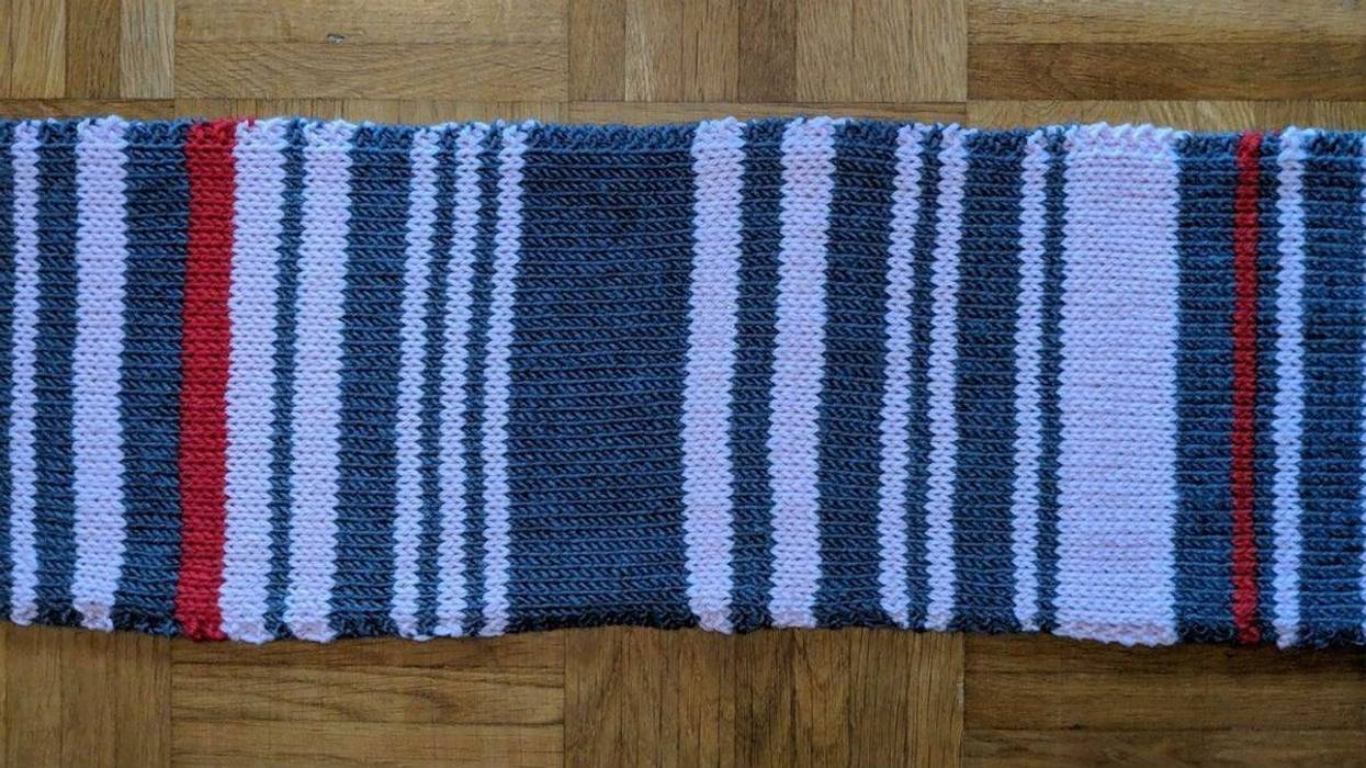 A woman is recording her commuter train delays by knitting them on a scarf