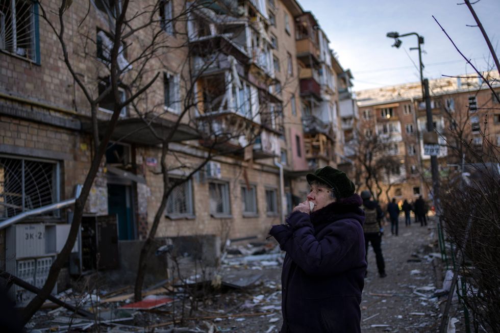 A woman looks at residential buildings damaged by a bomb in Kyiv, Ukraine, Friday, March 18, 2022. Russian forces pressed their assault on Ukrainian cities Friday, with new missile strikes and shelling on the edges of the capital Kyiv and the western city of Lviv, as world leaders pushed for an investigation of the Kremlin