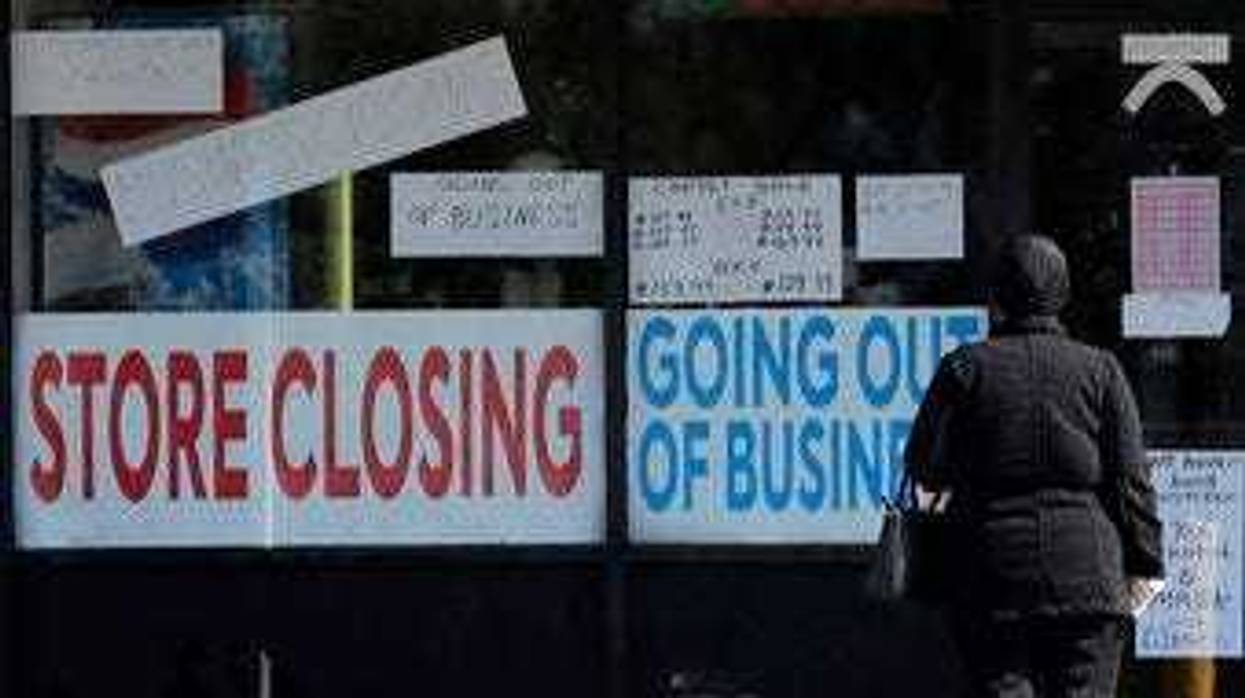 A woman looks at signs at a store closed due to COVID-19 in Niles, Ill., Wednesday, May 13, 2020. (AP Photo/Nam Y. Huh)