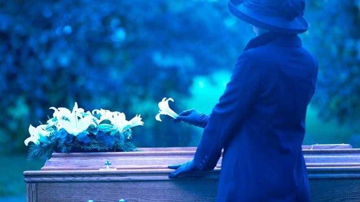 a woman placing a flower on a coffin